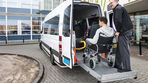 man in wheel chair on lift at back of van