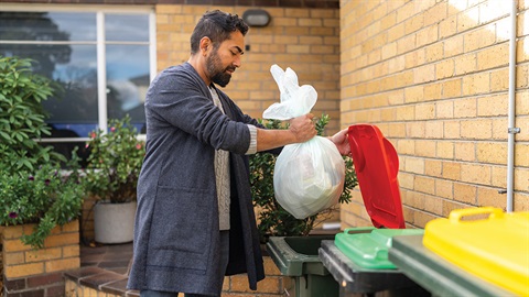 Resident placing a bag of rubbish in the waste bin