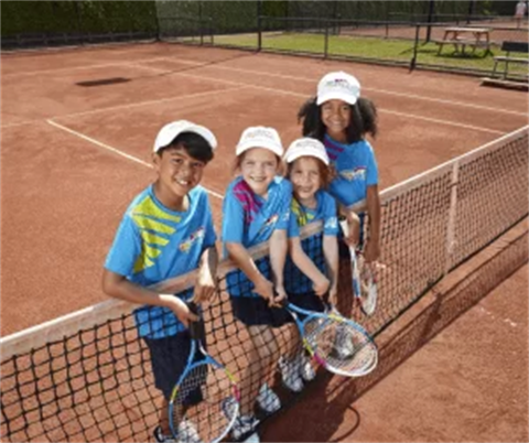 children leaning on tennis court net