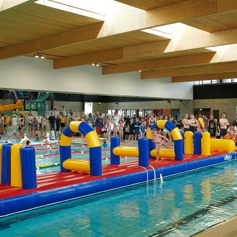 Kids on a blowup climbing inflatable on top of the water