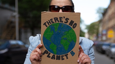 Person holding a sign on recycled cardboard that says there is no planet B